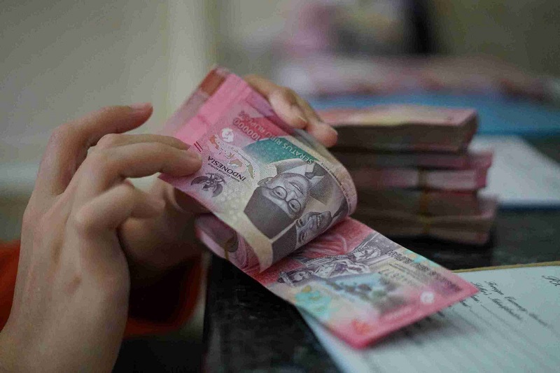 Kasir menghitung uang Rupiah saat melayani pengunjung yang menukar Dollar USA di PT Latunrung Money Changer Juanda. Foto: Abbas/KabarBursa.com